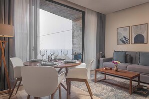 Ein modernes Wohnzimmer mit Essbereich, einer Couch, einem Couchtisch und Kunstwerken an der Wand.