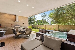 An outdoor patio with a dining area, seating, a hot tub, and a view of the surrounding greenery. - Last Minute Disney Getaway! Private Hot Tub & Modern Townhouse. Book Now! #166731 (Orlando)