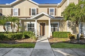 A two-story residential building with a front entrance, a covered porch, and a well-maintained lawn with palm trees and shrubs. - Last Minute Disney Getaway! Modern Townhouse. Book Now! #166743 (Orlando)