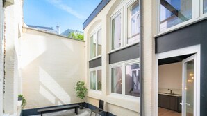 A courtyard with a bench, a potted plant, and a view of the interior through a glass door. - Saint Pauls Deluxe Apartment (Antwerp)