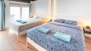 A bedroom with two beds, a window with curtains, and a bedside table with a lamp. - Saint Pauls Deluxe Apartment (Antwerp)