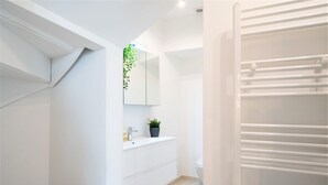 A modern bathroom with a white vanity, a mirror, a potted plant, and a towel rack. - Saint Pauls Deluxe Apartment (Antwerp)