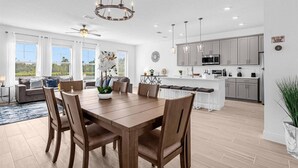 Una cocina amplia con electrodomésticos modernos, un comedor con mesa y sillas de madera, y un ventanal grande con vistas a un jardín.