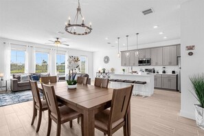 A spacious kitchen with modern appliances, a dining area with a wooden table and chairs, and a large window overlooking a garden. - Last Minute Disney Getaway! Modern Spacious Townhouse. Book Now! #167211 (Orlando)