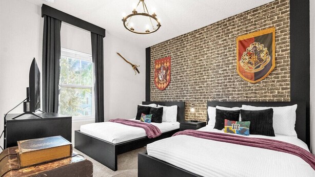 Une chambre avec deux lits, un mur en briques, une télévision et une bibliothèque.