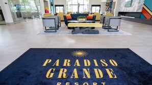 Un área de recepción con alfombra azul, un sofá, sillas y una mesa de centro.