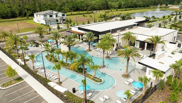 Un hotel moderno con piscina, sillones de descanso y palmeras.