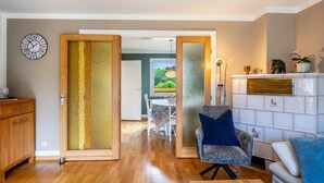 Un salon moderne avec un meuble en bois, un fauteuil bleu, un canapé blanc et une cheminée agrémentée d’objets décoratifs.