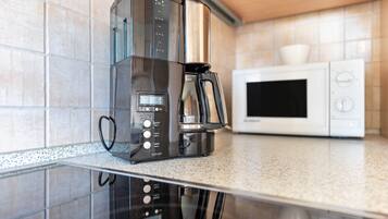 Eine Küche mit Kaffeemaschine und Mikrowelle auf einer Arbeitsplatte.