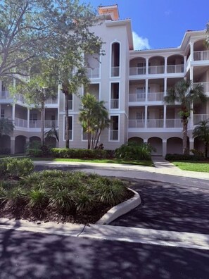 A multi-story hotel with balconies, a landscaped courtyard, and a clear sky. - Naples Lakes Country Club Condo | Golf Included | Resort Pool, Pickle Tennis (Naples)