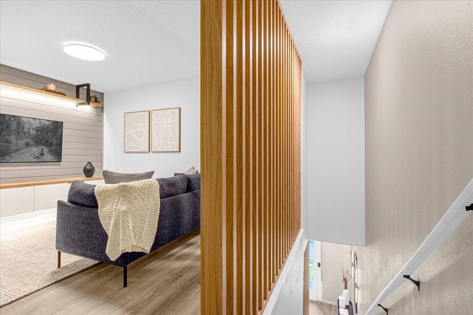 Un salon moderne avec un canapé, un mur décoratif en bois et un téléviseur à écran plat.