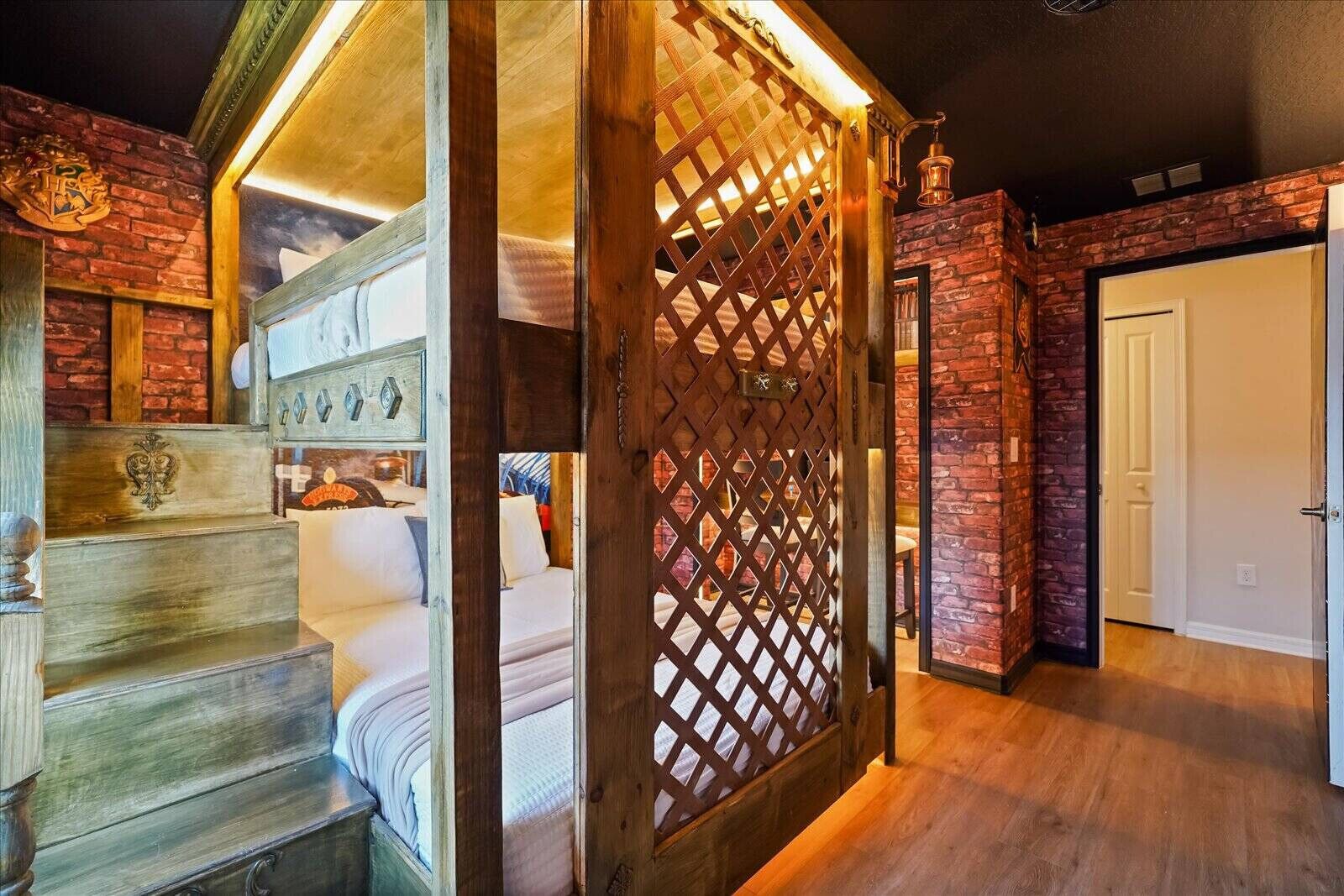 Ein Zimmer mit einer Holztreppe, einem Bett, einem Holzeinsatz mit Gitterstruktur und einer Ziegelwand.