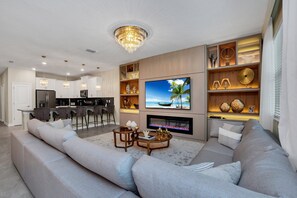 A modern living room with a large TV, a fireplace, and a bar area. - Last Minute Disney Getaway! Private Pool, Game Room & Themed Bedrooms. Book Now! #172197 (Orlando)