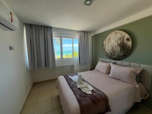 Ein Schlafzimmer mit Bett, Vorhängen, einem Wandbild und einem Fenster mit Blick.