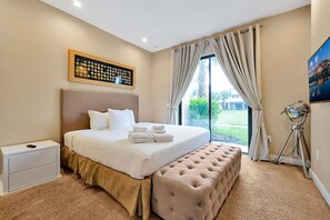 A hotel room with a large bed, a headboard, a bedside table, a lamp, and a view of the outdoors. - Last Minute Disney Getaway! Modern Townhouse & Private Terrace. Book Now! #165143 (Orlando)
