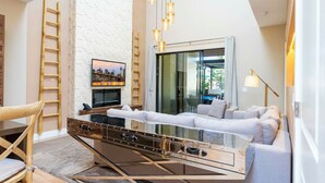 Ein modernes Wohnzimmer mit Glastisch, weißem Sofa und Stadtansicht am Fernseher.