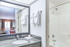 Un baño de hotel con lavamanos, espejo y ducha.