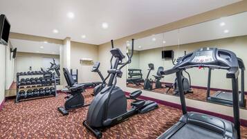 A hotel gym with treadmills, elliptical machines, and dumbbells.