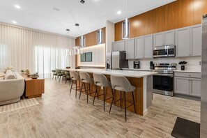 Une cuisine moderne dotée d’un îlot central, de tabourets de bar et d’appareils électroménagers intégrés.