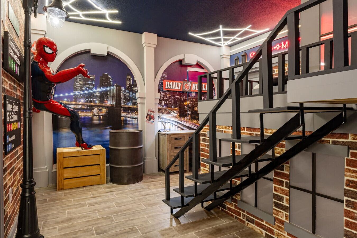 Une pièce comprenant une statue de Spiderman, une fresque représentant un paysage urbain, un escalier et un coin bar.