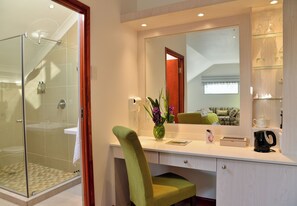 Een moderne badkamer met een douchecabine van glas, een wastafel met spiegel en een groene stoel.