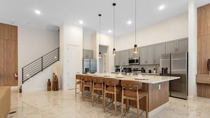 A modern kitchen with a central island, stainless steel appliances, and a staircase. - Last Minute Disney Getaway! Private Pool, Game Room & Themed Bedrooms. Book Now! #172545 (Orlando)