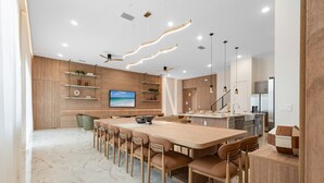 A modern kitchen with a large island, wooden cabinets, and a dining area with a long table and chairs. - Last Minute Disney Getaway! Private Pool, Game Room & Themed Bedrooms. Book Now! #172545 (Orlando)