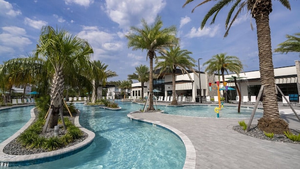 A pool area with palm trees, lounge chairs, and a building with a bar. - Last Minute Disney Getaway! Private Pool, Game Room & Themed Bedrooms. Book Now! #172545 (Orlando)