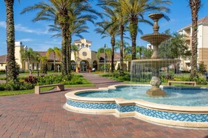 A courtyard with a fountain, palm trees, and a building with a clock tower. - Last Minute Disney Getaway! Beautiful Townhouse & Private Balcony. Book Now! #172665 (Orlando)