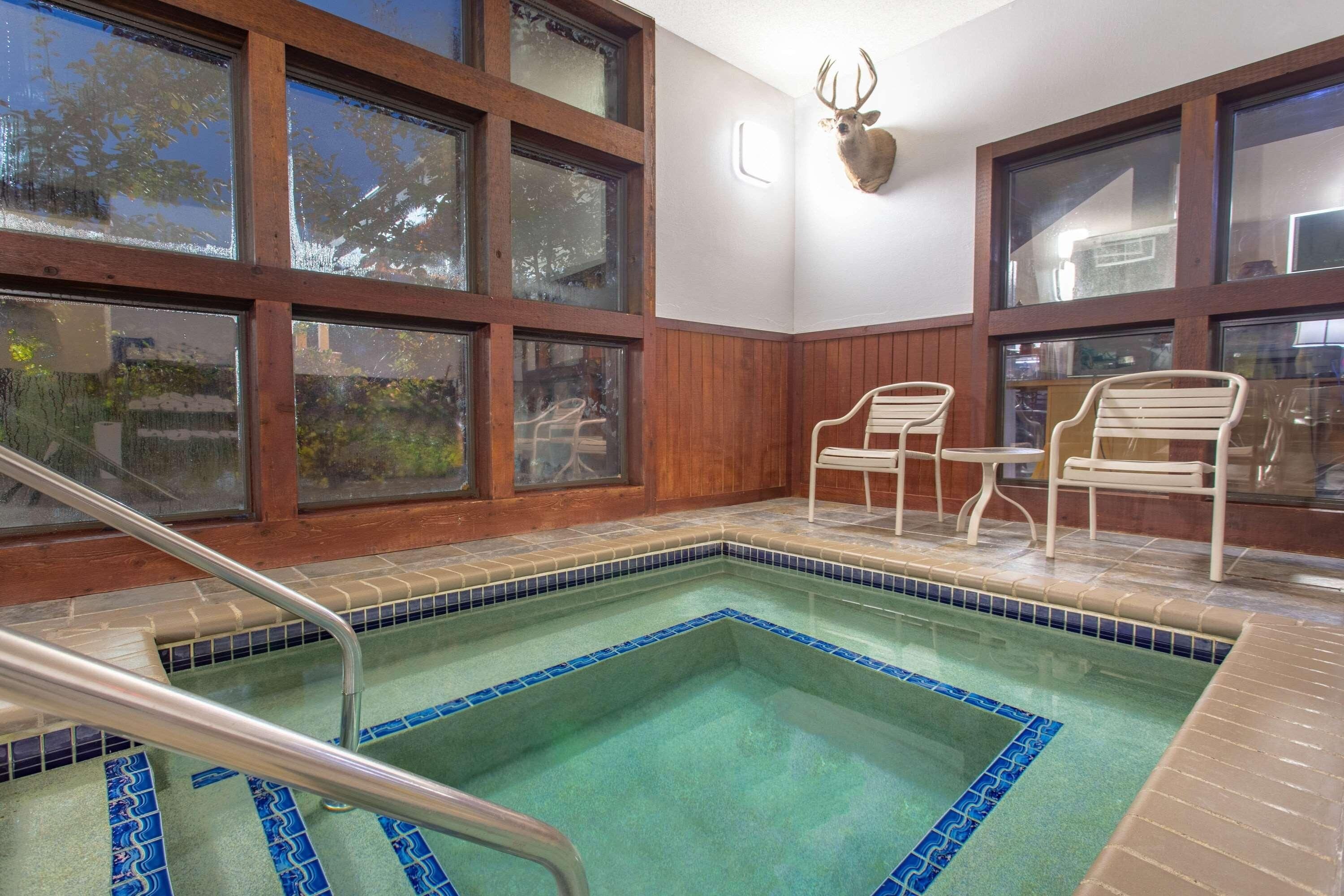 A pool area with a tiled border, wooden walls, and a deer head decoration.