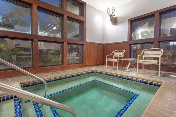 Uma área de piscina com borda de azulejos, paredes de madeira e uma decoração de cabeça de veado.