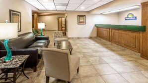 A hotel lobby with a reception desk, leather seating, a small table with a lamp, and a framed picture on the wall. - Days Inn by Wyndham Tiffin (Tiffin)