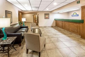 A hotel lobby with a reception desk, leather seating, a small table with a lamp, and a framed picture on the wall. - Days Inn by Wyndham Tiffin (Tiffin)