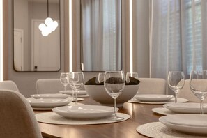 A dining area with a table set for four, including wine glasses and plates, with a bowl of fruit on the table. - Last Minute Disney Getaway! Private Pool & Themed Bedrooms. Book Now! #172689 (Orlando)