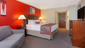 Een hotelkamer met een bed, twee bedlampen, een televisie, een bureau en een bank.