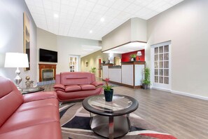 A spacious living area with a red sofa, a glass coffee table, and a fireplace. - Ramada Conference Center By Wyndham Lewiston (Lewiston)