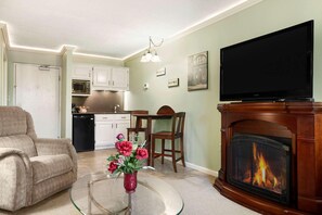 A living room with a fireplace, television, and a dining area with chairs and a table. - Ramada Conference Center By Wyndham Lewiston (Lewiston)