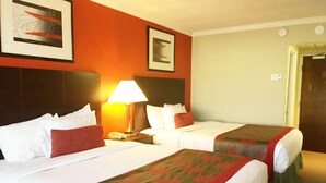 Een hotelkamer met twee bedden, een nachtkastje, een lamp en kunstwerken aan de wanden.