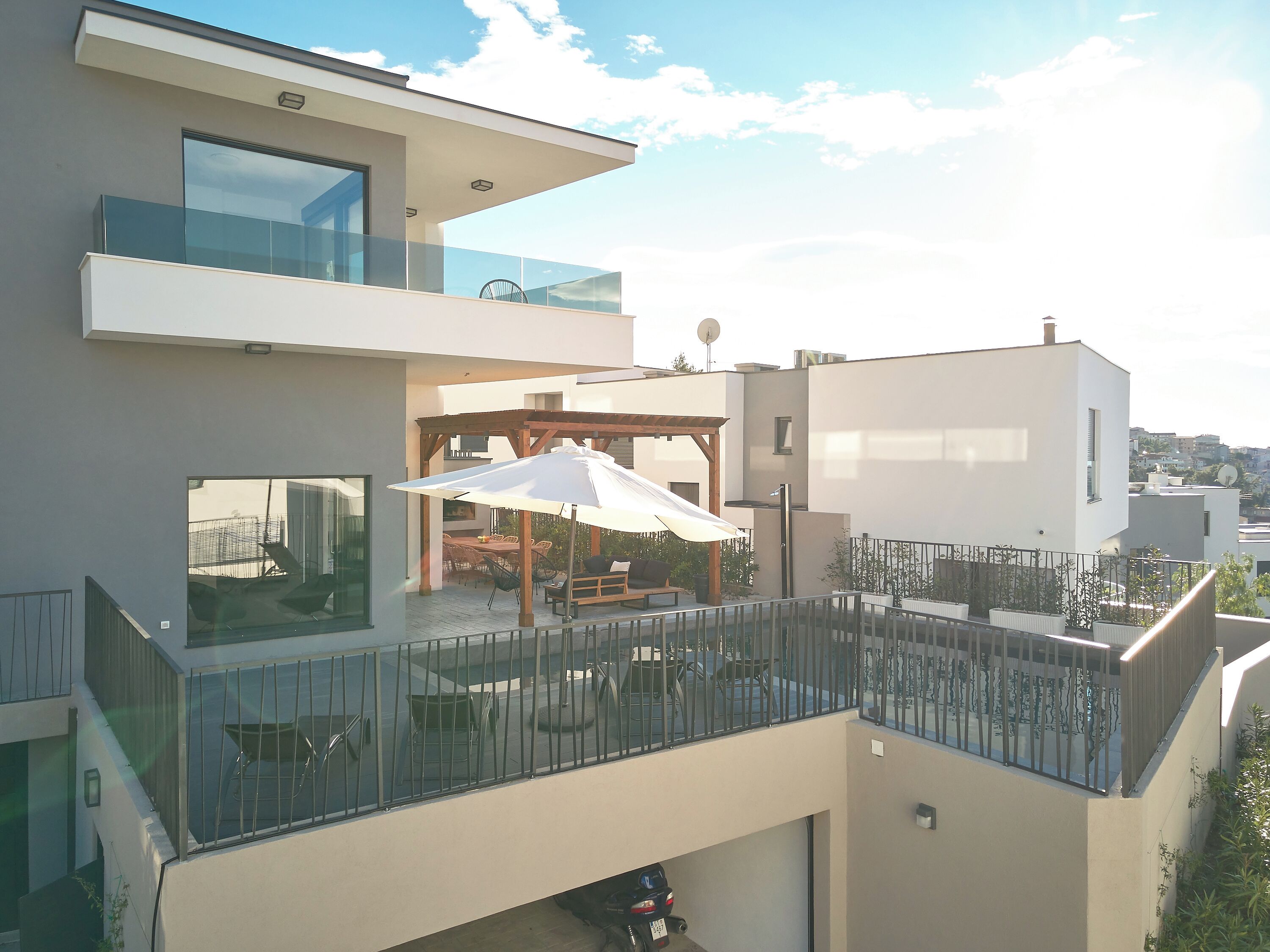 Un bâtiment moderne à deux étages, doté d’un balcon, d’un espace extérieur aménagé et offrant une vue sur le paysage urbain.