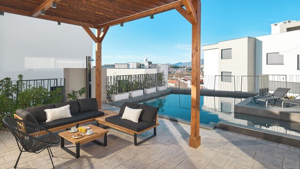 A rooftop terrace with a pool, outdoor seating, and a view of the city. - Luxury villa Natali with pool (Podstrana)