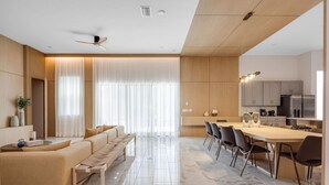 Uma sala de estar moderna com sofá, mesa de jantar com cadeiras, ventilador de teto e uma área de cozinha com armários e eletrodomésticos.