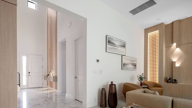 Um interior moderno com piso de mármore, um sofá bege e um armário de madeira.