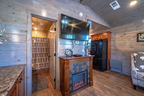 Un interior de madera con chimenea, televisor y refrigerador.