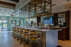 A bar area with a marble countertop, multiple stools, and a television screen displaying a sports game. - Last Minute Disney Getaway! Private Pool, Game Room & Themed Bedrooms. Book Now! #172899 (Orlando)