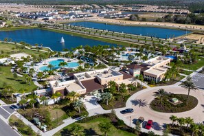 An aerial view of a resort with a large pool, palm trees, and a bridge over a body of water. - Last Minute Disney Getaway! Private Pool, Game Room & Themed Bedrooms. Book Now! #172899 (Orlando)
