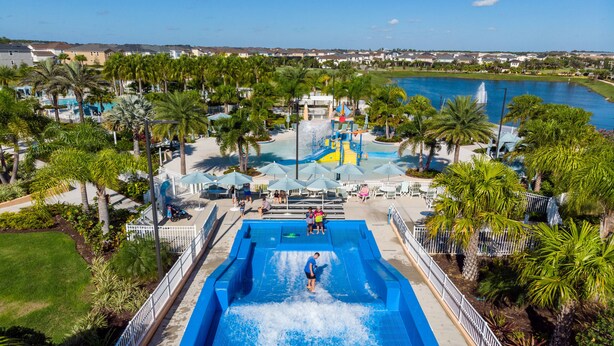 Un parc aquatique doté d’une grande piscine, de palmiers et offrant une vue sur le quartier environnant.