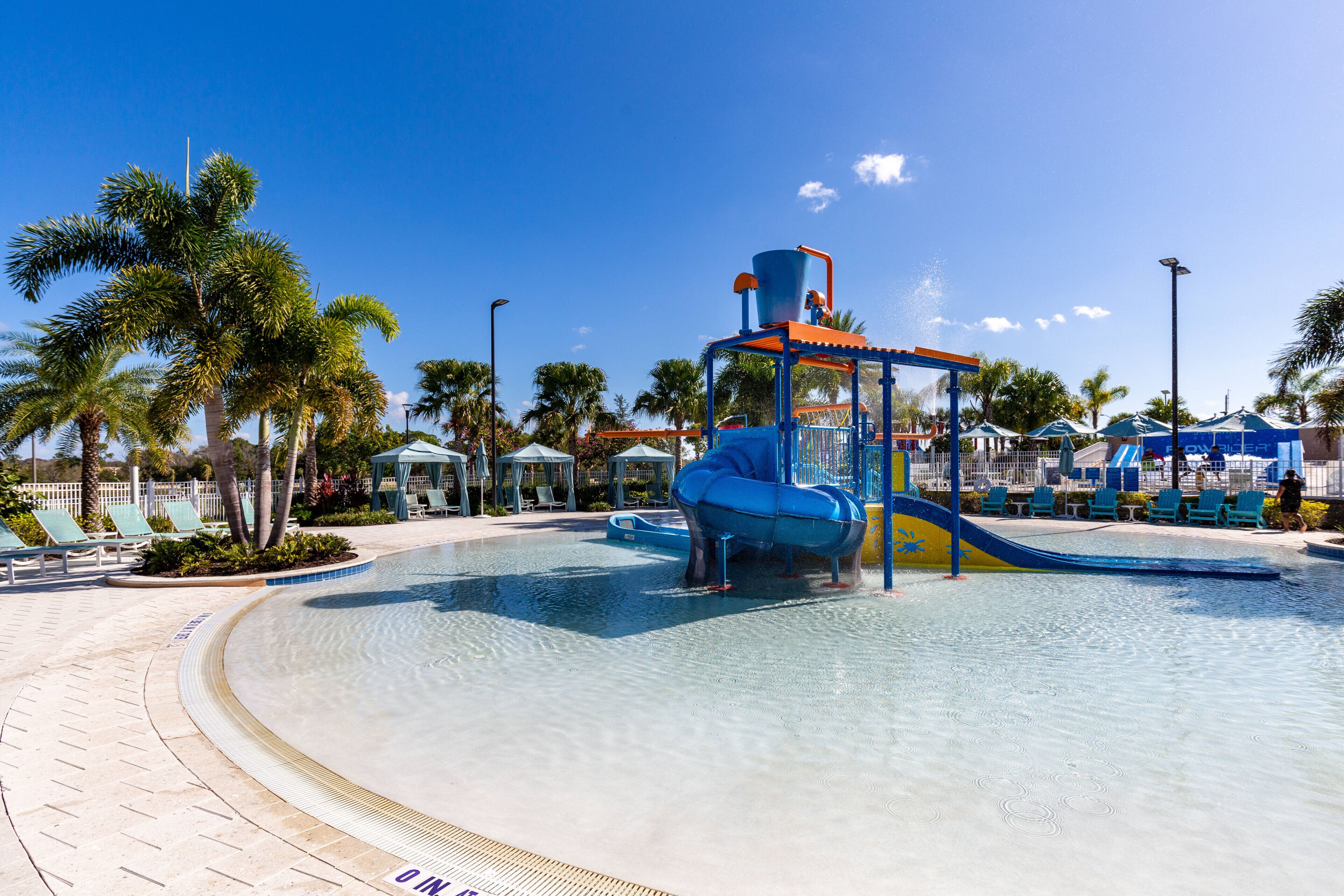 A water park with a large pool, slides, and palm trees.