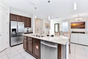 Una cocina moderna con un refrigerador de acero inoxidable, lavavajillas integrado y encimera de granito.