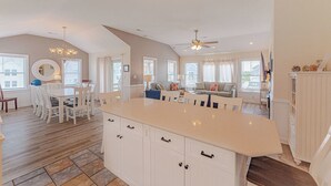 Een ruime keuken met een groot eiland, een eethoek en een gezellige woonkamer met een bank en televisie.