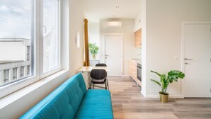 A modern apartment with a sofa, dining table, chairs, a kitchen, and a large window. - Cosy Apartment in Antwerp Centre (Antwerp)
